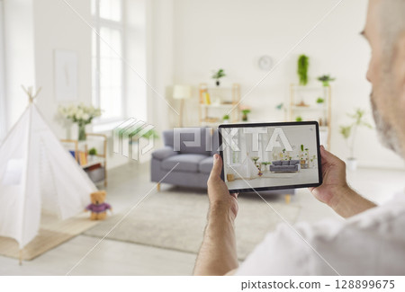 Man Holding Tablet with View of Modern Kids Room 128899675