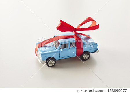 Blue Toy Car with Red Ribbon on White Background Blue Toy Car with Red Ribbon on White Background 128899677