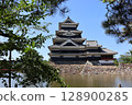 Matsumoto Castle, shining against the summer sky, seen from behind a tree 128900285