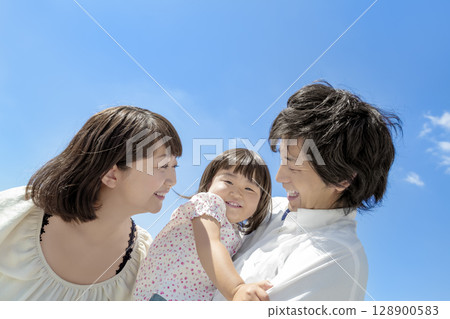 Three-person family playing in the park 128900583