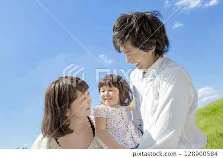 Three-person family playing in the park 128900584