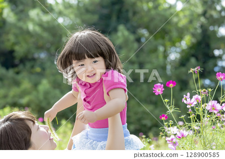 Mother and daughter playing in a cosmos field 128900585