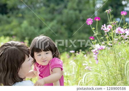 Mother and daughter playing in a cosmos field 128900586