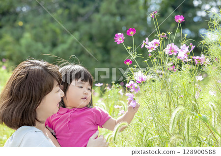 Mother and daughter playing in a cosmos field Mother and daughter playing in a cosmos field 128900588