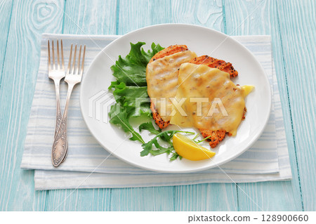 grilled chicken breast topped with melted cheese 128900660