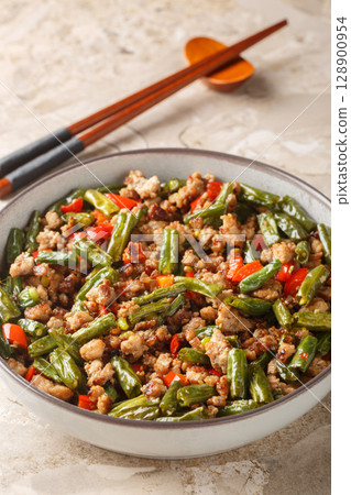 Stir fried chinese green beans with crispy pork, bell pepper, garlic and ginger close-up in a bowl. Vertical Stir fried chinese green beans with crispy pork, bell pepper, garlic and ginger close-up in a bowl. Vertical 128900954