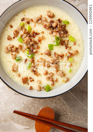 Asian Steamed Eggs with fried Pork mince and green onion closeup in the bowl. Vertical top view Asian Steamed Eggs with fried Pork mince and green onion closeup in the bowl. Vertical top view 128900961
