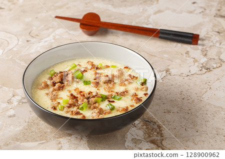 Tender steamed eggs with crispy fried pork and green onions close-up in a bowl. Horizontal Tender steamed eggs with crispy fried pork and green onions close-up in a bowl. Horizontal 128900962