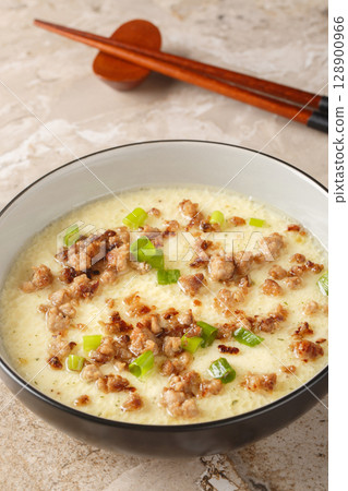 Steamed Eggs with Crispy Pork and green onion closeup in the bowl. Vertical Steamed Eggs with Crispy Pork and green onion closeup in the bowl. Vertical 128900966