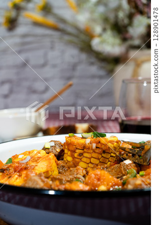 Delicious beef stew called carbonada with corn, potatoes, and carrots simmering in rich tomato sauce 128901478