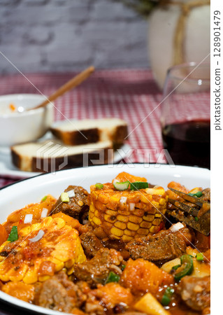Brazilian corn, meat, and pumpkin stew called carbonada with wine and bread 128901479