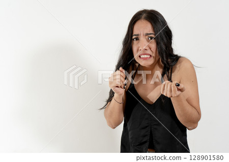 Young latin woman showing disgust and stress on white background Young latin woman showing disgust and stress on white background 128901580