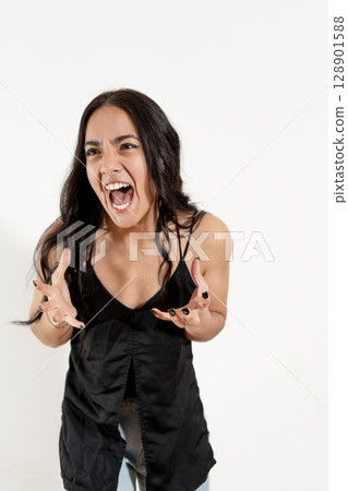 Studio portrait of an enraged hispanic woman screaming and gesturing with her hands 128901588