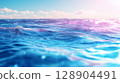 Vibrant ocean waves under bright sky with soft clouds 128904491