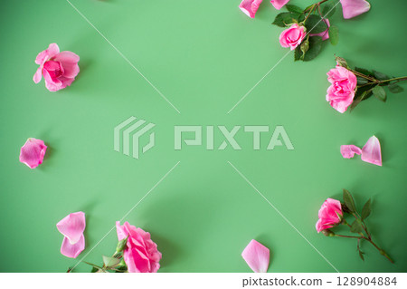 Branches of pink roses on a green background from above Branches of pink roses on a green background from above 128904884
