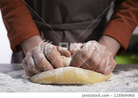 Baking concept. Caucasian female hands kneading the dough. 128904960
