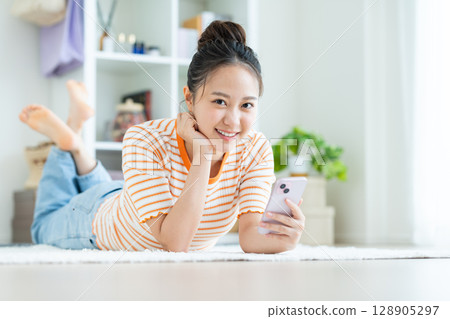 年輕女子在客廳看智慧型手機 年輕女子在客廳看智慧型手機 128905297