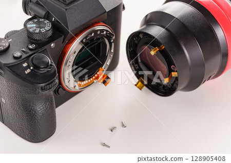 A broken lens, professional camera and repair tools on a white table. A broken lens, professional camera and repair tools on a white table. 128905408