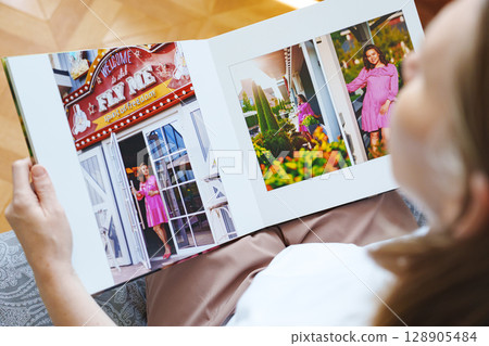 woman is holding and flipping through a photo book with a pregnancy photo shoot 128905484