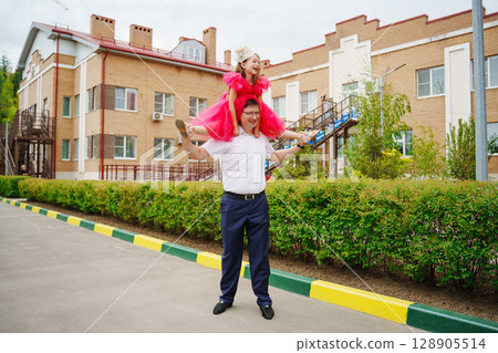 Happy well-dressed family on a walk. Dad and little daughter Happy well-dressed family on a walk. Dad and little daughter 128905514