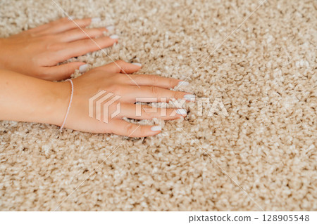 a woman's hand touching the beige Interior pile carpet made of polypropylene.  128905548