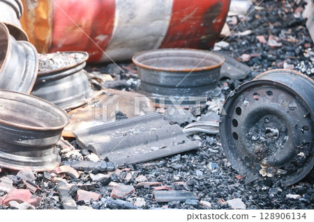 A pile of rusted and burnt car parts, including a tire A pile of rusted and burnt car parts, including a tire 128906134