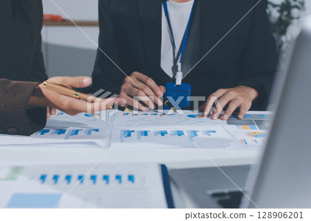 Focused young businessman signing agreement with skilled lawyer in eyeglasses. Concentrated financial advisor showing place for signature on paper contract document to male client at meeting in office 128906201