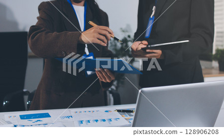 Focused young businessman signing agreement with skilled lawyer in eyeglasses. Concentrated financial advisor showing place for signature on paper contract document to male client at meeting in office Focused young businessman signing agreement with skilled lawyer in eyeglasses. Concentrated financial advisor showing place for signature on paper contract document to male client at meeting in office 128906208