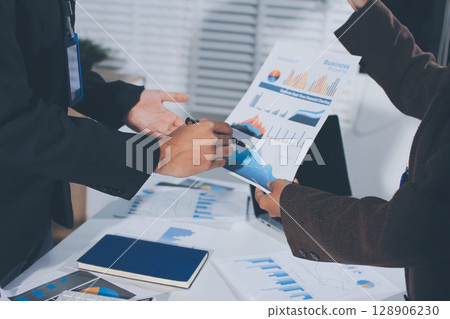 Focused young businessman signing agreement with skilled lawyer in eyeglasses. Concentrated financial advisor showing place for signature on paper contract document to male client at meeting in office 128906230