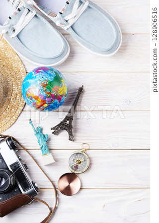 Travel planning simple background of compass, film camera, straw hat, moccasins, globe and souvenirs on white planks flat lay with copy-space Travel planning simple background of compass, film camera, straw hat, moccasins, globe and souvenirs on white planks flat lay with copy-space 128906516