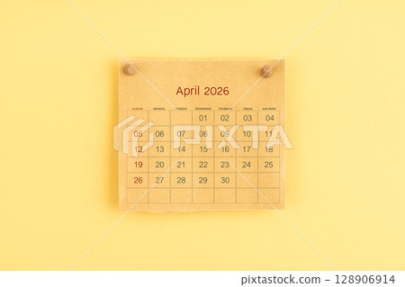 April 2026 brown calendar with wooden thumbtack on yellow color background. 128906914