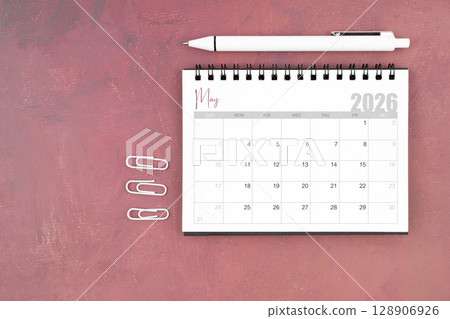 Desk calendar for May 2026 and pen with paper clips on red table, Flat lay. Desk calendar for May 2026 and pen with paper clips on red table, Flat lay. 128906926