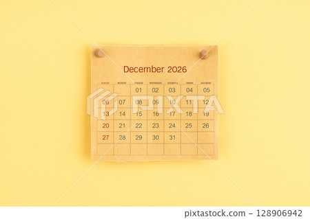 December 2026 brown calendar with wooden thumbtack on yellow color background. 128906942