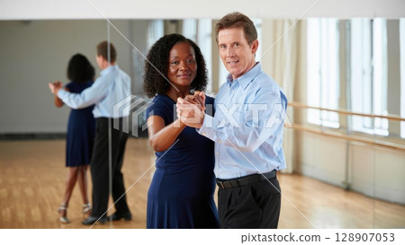 Diverse couple dances together in a bright ballroom, enjoying movement and learning in professional dance studio. Generative AI. 128907053