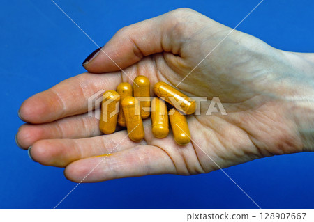 Curcumin supplement pills in hand 128907667