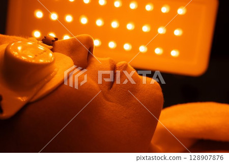 Skin treatment session under bright orange lights at a wellness center Skin treatment session under bright orange lights at a wellness center 128907876