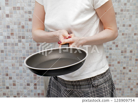 Housewife holding empty frying pan 128909754