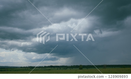 A dramatic sky looms over a beautiful green landscape, capturing natures unique mood 128909893