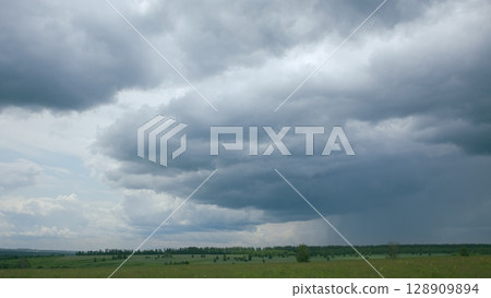 The Dramatic Cloudy Skies That Sweep Over the Expansive Green Landscape Below Them 128909894