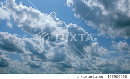 The scene presents majestic cloudscapes gracefully floating under a beautifully clear sky 128909986