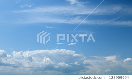 A Serene Blue Sky adorned with Fluffy White Clouds creating a peaceful and beautiful atmosphere 128909994