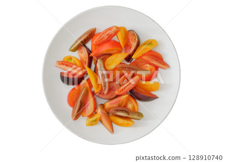 Sliced tomato in white plate. Tomatoes in a clay plate isolate on white background. Orange and red ripe vegetables. Top view. 128910740