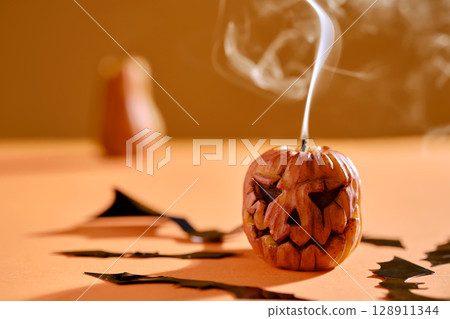 Halloween-style candles on a orange background. Festive decor. 128911344