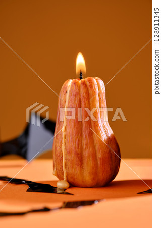 Halloween-style candles on a orange background. Festive decor. 128911345
