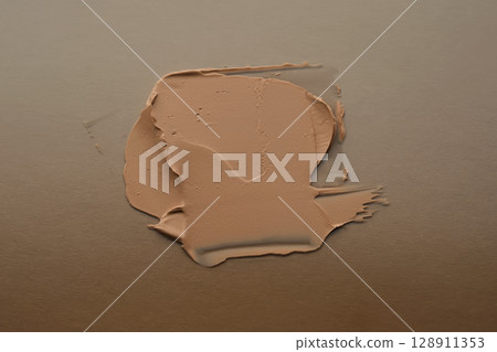 The texture of foundation on a beige background. The texture of foundation on a beige background. 128911353