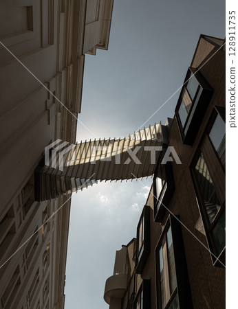 View from below of The futuristic modern of Twisted sky bridge connecting Royal opera house to Royal ballet school in Covent garden. 128911735