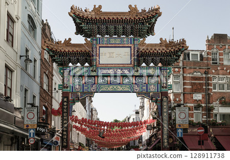 Stunning of London Chinatown entrance gate in traditional chinese design with glazed yellow tiles, a golden dragon, painted panels, two white jade plaques and red lanterns. Stunning of London Chinatown entrance gate in traditional chinese design with glazed yellow tiles, a golden dragon, painted panels, two white jade plaques and red lanterns. 128911738