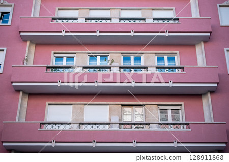 Pink Apartment Building with Balconies and Windows Pink Apartment Building with Balconies and Windows 128911868