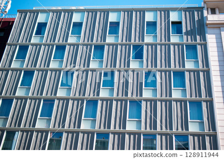 Modern Facade with Vertical Ribbing and Blue-Tinted Windows Modern Facade with Vertical Ribbing and Blue-Tinted Windows 128911944