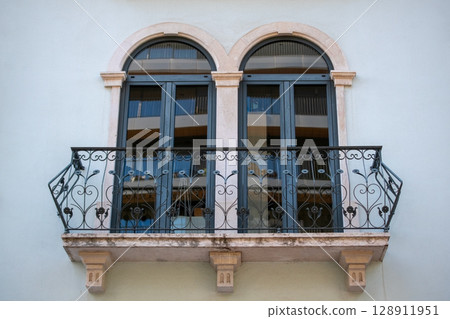 Elegant Balcony with Arched Windows and Ornate Ironwork Elegant Balcony with Arched Windows and Ornate Ironwork 128911951